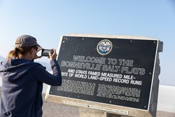 Young woman taking a photo of the bonneville salt flats sign in utah
