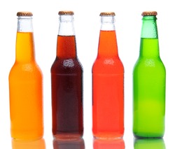 Four assorted soda bottles on white with reflection.
