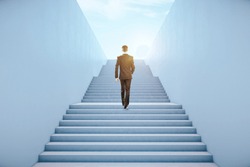 Back view of young businessman climbing abstract bright concrete sky stairs. Career development and growth concept 