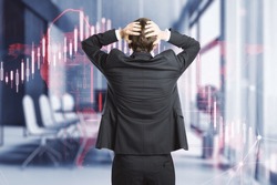 Back view of stressed businessman with glowing falling red forex chart on blurry office interior background. Stock exchange and crisis concept. Double exposure