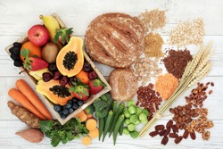 Healthy high fibre diet food concept with legumes, fruit, vegetables, wholegrain bread, cereals, grains, nuts and seeds. Super foods high in antioxidants, anthocyanins, omega 3 and vitamins. Top view.