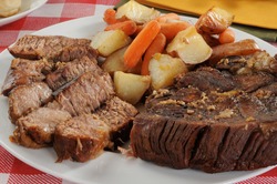 A sliced beef pot roast with autumn vegetables