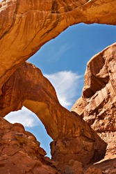 The red rock of Utah's Arches National Park, with blue sky and white clouds seen through one of the arches.