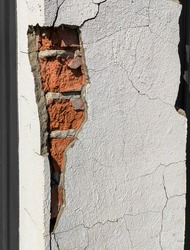 Cracked plaster in a brick wall as an abstract background.