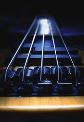 Closeup view of bridge of five strings bass guitar, highlighted shapes.