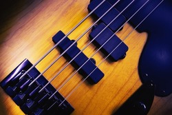 Closeup view of bridge and pickups of five strings bass guitar, highlighted shapes.