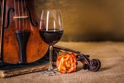 Classical old, used violins detail with red wine glass 