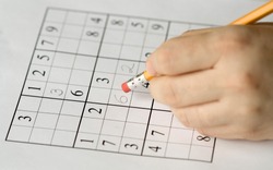sudoku puzzle and hand erasing, focus on mistake