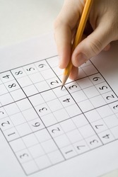 sudoku puzzle and hand holding pencil