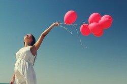 Young pregnant woman holding red balloons. Photo in old color image style.