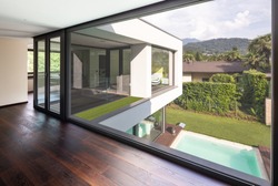 Large window in hallway of modern villa overlooking the private pool. Nobody inside