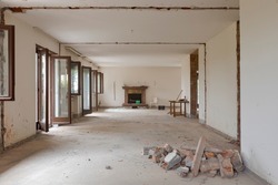 Large bright room with many windows of an old villa undergoing demolition and renovation. The walls have been knocked down and the floor is gone. Nobody inside