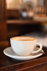Cup of cappuccino on coffee bar with blurred background