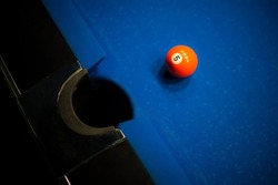 orange billiard ball number one is on the blue table at the pocket