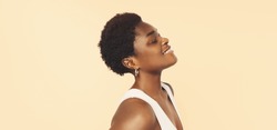 Beautiful black woman . Beauty portrait of african american woman with clean healthy skin on beige background. Smiling beautiful afro girl.Curly black hair 