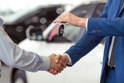 Handshake of two businessmen when selling a car in a motor show, close-up