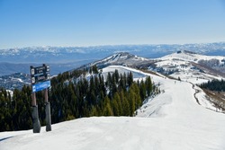 Trail sign at Park City Ski Area, Utah. Top view to the valley with montains range during early spring weather conditions. 