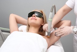 Blonde woman having underarm Laser hair removal epilation. Laser treatment in cosmetic salon