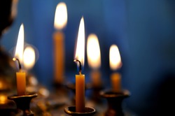 Burning candles in sconces on black blue background