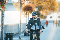 Hipster businessman commuter with electric bicycle traveling home from work in city.