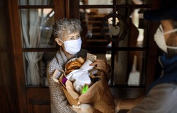 Courier delivering shopping to senior woman with face mask, corona virus and quarantine concept.