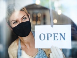 Coffee shop woman owner with face mask, open after lockdown quarantine.