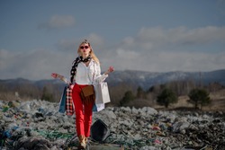 Woman with shopping bags on landfill, consumerism versus pollution concept.