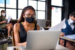Business people with face masks indoors in office, back to work after coronavirus lockdown.