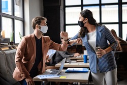 Business people with face masks greeting indoors in office, coronavirus concept.