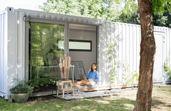 Mature woman working in home office in container house in backyard.