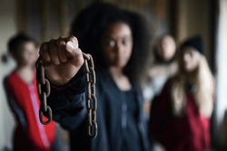 Portrait of mixed-race teenager girl with chain indoors in abandoned building.