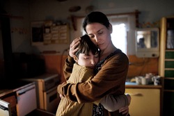 Portrait of sad poor mature mother hugging small daughter indoors at home, poverty concept.