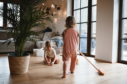 Two small children sweeping at home, daily chores concept.