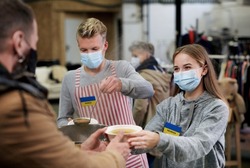 Volunteers serving hot soup for Ukrainian migrants in refugee centre, Russian conflict concept.