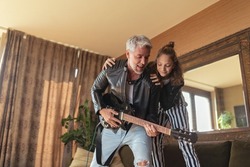 Father rock guitarist having fun and and dancing with his teenage daughter at home.