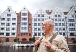 Senior man tourist outdoors sightseeing in historic town.