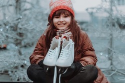 Cute girl at outdoor ice skating rink looking forward to going ice skating. Winter fun during the Christmas holidays.