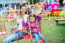 Mother and daughter at fun fair, chain swing ride
