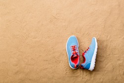 Blue sports shoes laid on sand beach, studio shot