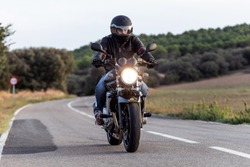Shot of young man biker having fun driving the empty highway on a motorcycle tour journey.