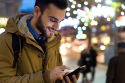 Outdoor portrait of young man using his mobile phone at night.