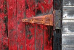 Rustic red door on white shed with hinge and peeling red paint