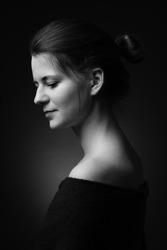beautiful female portrait with bare shoulders side profile view on dark background monochrome