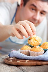 Chef is decorating delicious organic muffins. Almond and cherry cup cakes in natural setting.