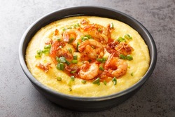 Delicious yellow grits with cheese, shrimps and bacon close-up in a plate on the table. horizontal