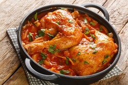 Homemade baked chicken with spicy onion tomato sauce close-up in a frying pan on the table. horizontal