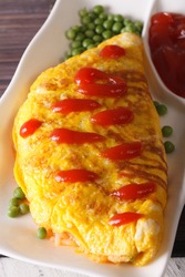 Delicious Omurice omelette with ketchup close-up on a plate. vertical