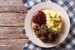fried meatballs, lingonberry sauce with potato garnish on a plate. horizontal view from above