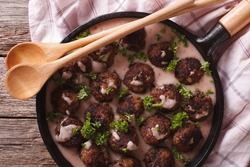 meatballs with creamy berry sauce closeup on a frying pan. horizontal view from above