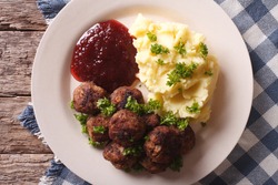 Swedish meatballs kottbullar, lingonberry sauce with a side dish mashed potato on the plate closeup. horizontal view from above